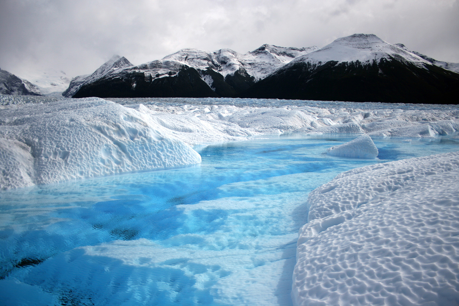 Image of massive blue glacier towering over a Patagonian fjord